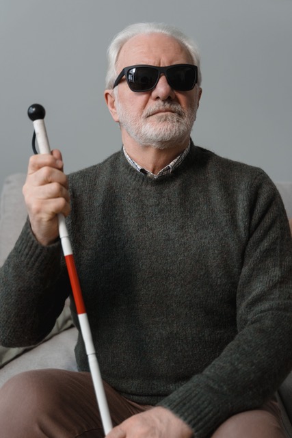 Man wearing sunglasses and holding a white cane