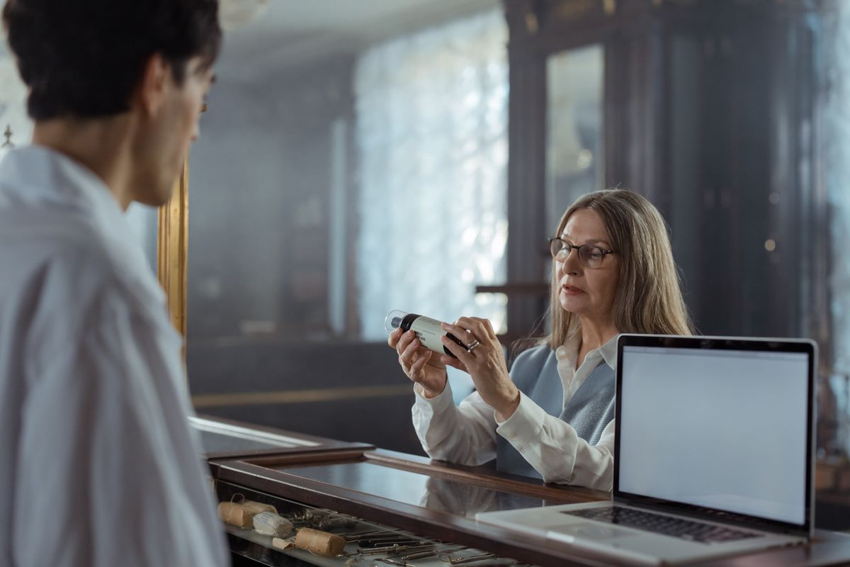 Woman discussing a medicine bottle at a pharmacy counter